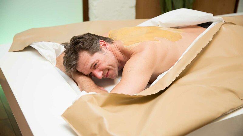 Eine lächelnder Mann bei einer Rücken-Behandlung  bequem liegend im Soft-Pack-System des NatureSpas