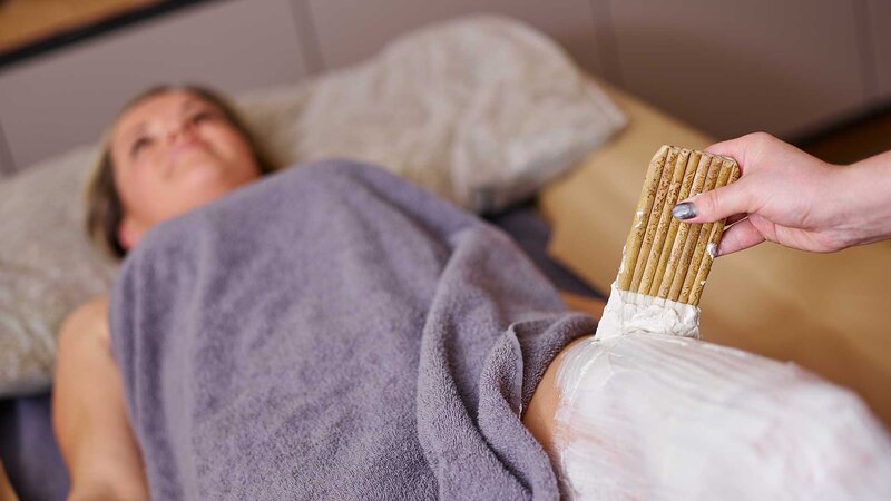 Ein Hotelgast bei einer wohltuenden Körperbehandlung im NatureSpa des Hotel Alpeiner im Stubaital