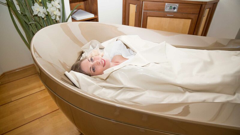 Eine lächelnde Frau bei einer Kosmetik-Behandlung bequem liegend im Soft-Pack-System des NatureSpas