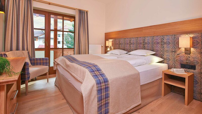 Einblick in den Schlafbereich eines Doppelzimmers mit Balkon im Hotel Alpeiner im Stubaital