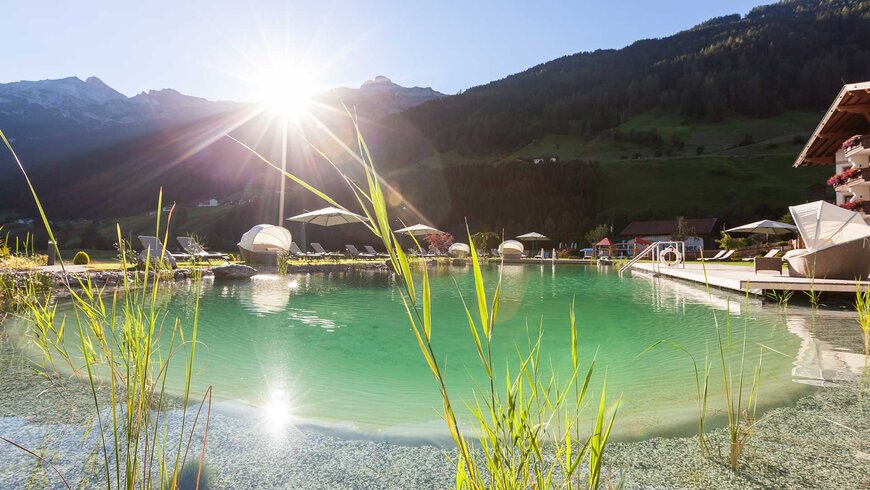 Ein schöner Naturbadesee mit Sonnenliegen für einen tollen Wellness-Urlaub im Stubaital.