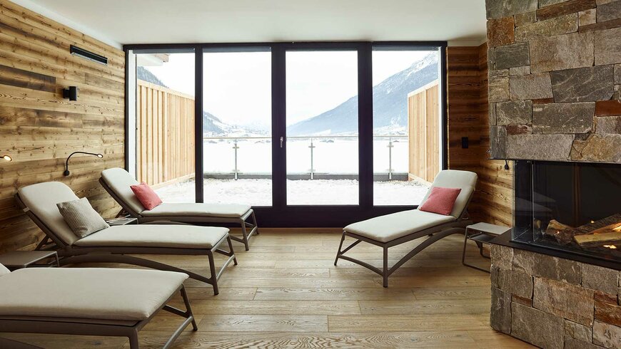Einblick in einen Ruheraum mit Kamin und Liegen im Wellnessbereich des Alpeiner Nature Resorts