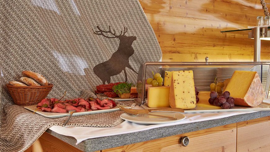 Traditionelles alpines Buffet mit einer Auswahl an Käse, Trauben und Fleisch.