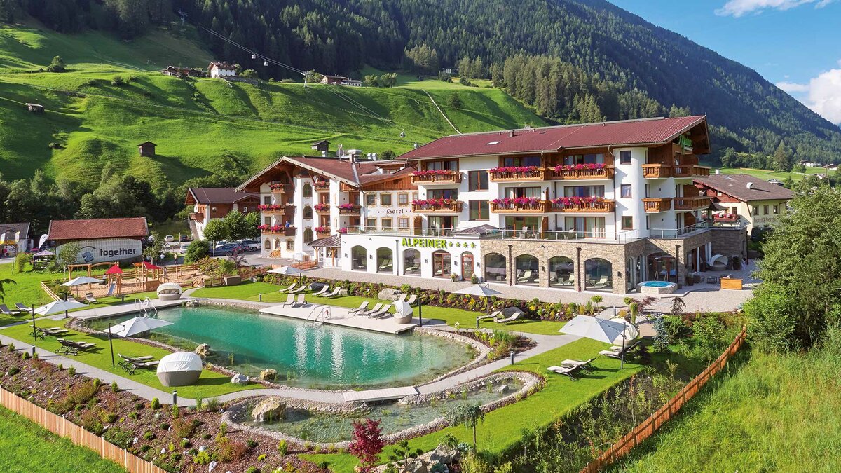 Außenansicht des Alpeiner Nature Resorts mit dem Naturbadeteich im Vordergrund