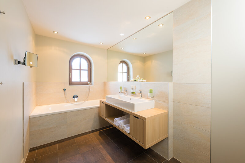 Einblick in das Bad in der Suite zum Wohlfühlen mit einem großen Spiegel und einer Badewanne