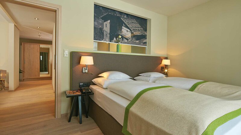 Einblick in das Schlafzimmer einer Suite mit extra langen Betten im Alpeiner Nature Resort in Neustift