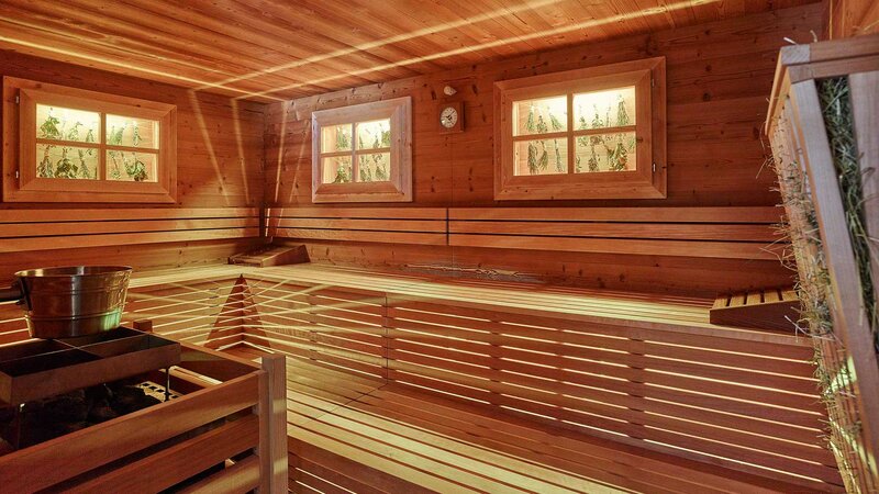 Einblick in eine große in Holz verkleidete Bio-Sauna mit kleinen Fenstern im Wellnessbereich des Alpeiner Nature Resorts