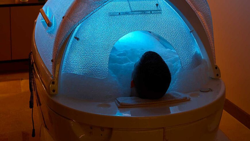 Ein Mann bei einem entspannenden Bad mit einer speziellen Lichtbehandlung im NatureSpa des Hotel Alpeiner im Stubaital