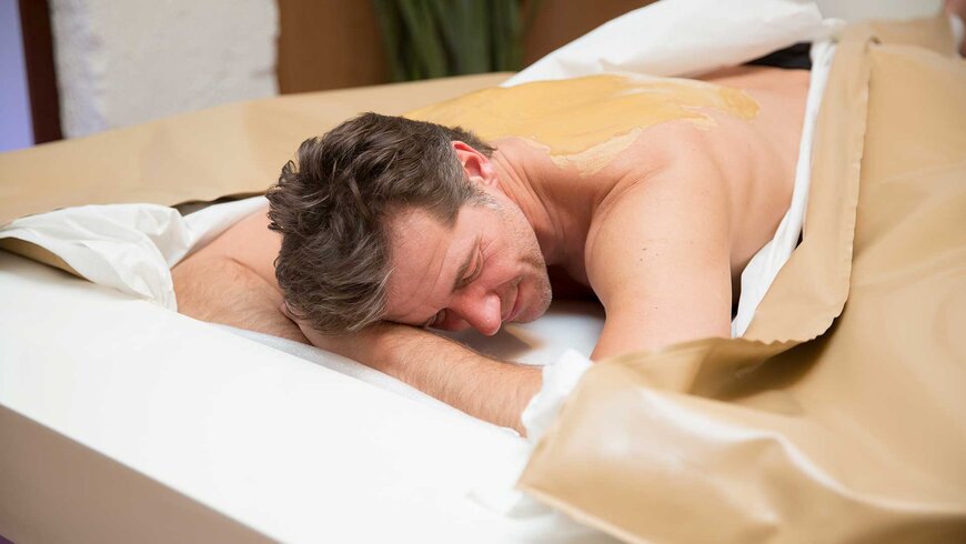 Mann genießt eine entspannende Schlammpackung im Wellnessbereich eines Tiroler Hotels.