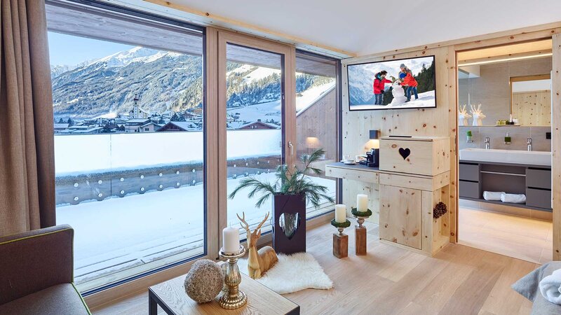 Einblick in ein gemütliches, lichtdurchflutetes Hotelzimmer mit Balkon mit Blick auf die Berge des Stubaitals 