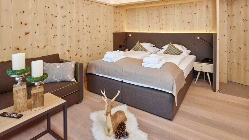 Einblick in den Schlafbereich eines gemütlich in Holz gekleideten Hotelzimmers