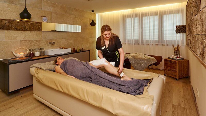 Ein Hotelgast bei einer wohltuenden Körperbehandlung im NatureSpa des Hotel Alpeiner im Stubaital