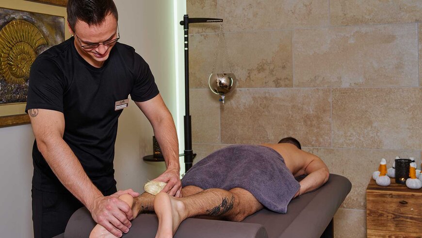 Ein Masseur verwöhnt einen Gast mit einer entspannenden Beinmassage im Spa-Bereich eines Hotels.