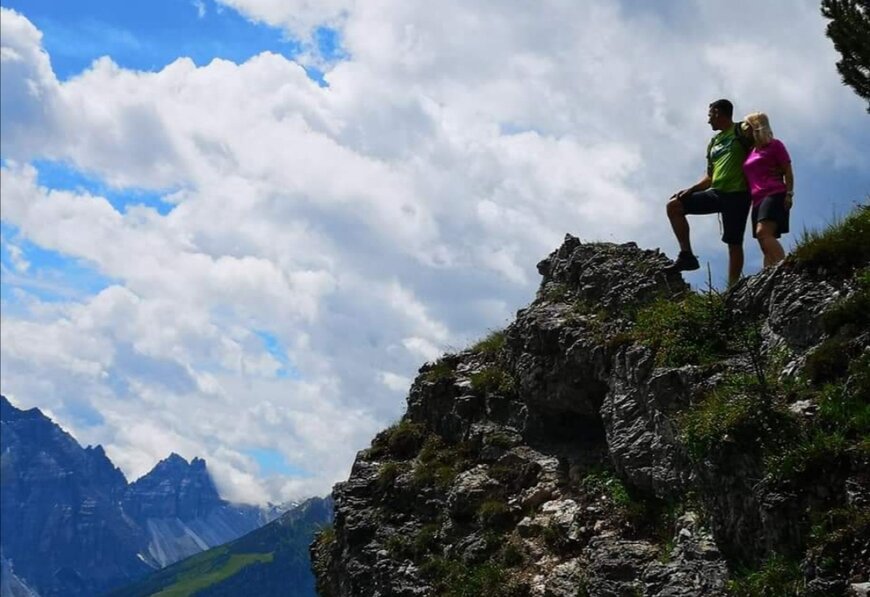 Zwei Wanderer genießen die atemberaubende Aussicht von einem felsigen Aussichtspunkt in den Tiroler Alpen.