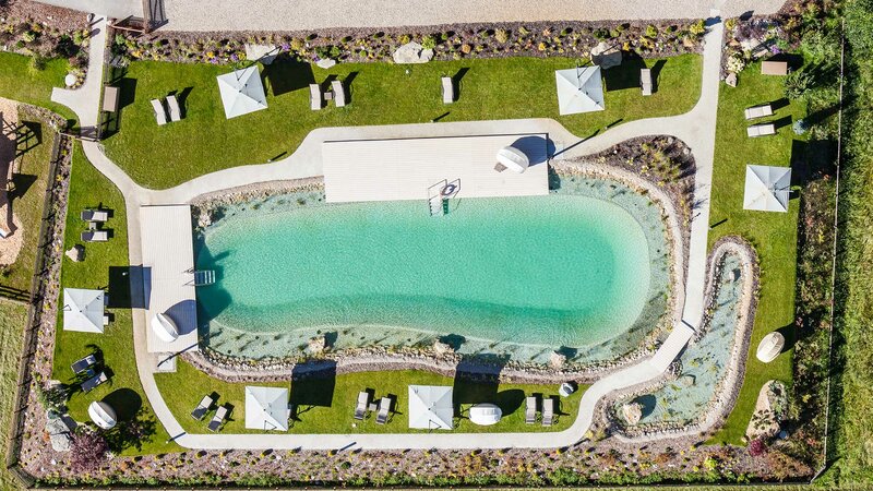 Der smaragdgrüne Naturbadeteich des Alpeiner Nature Resorts aus der Vogelperspektive