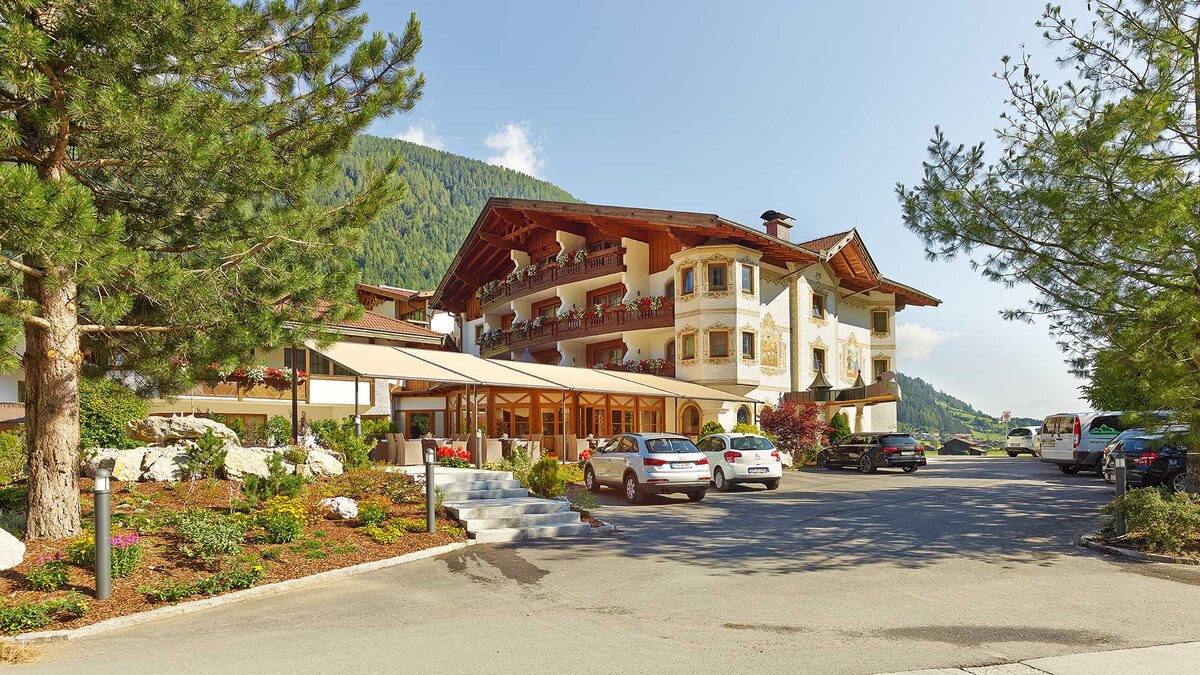 Sommerliche Außenansicht des Alpeiner Nature Resort im Stubaital mit Parkplatz 