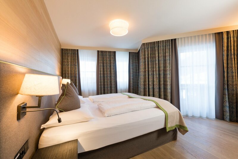 Ausschnitt des Schlafbereichs mit großem Doppelbett und bodentiefen Fenstern in der Suite
