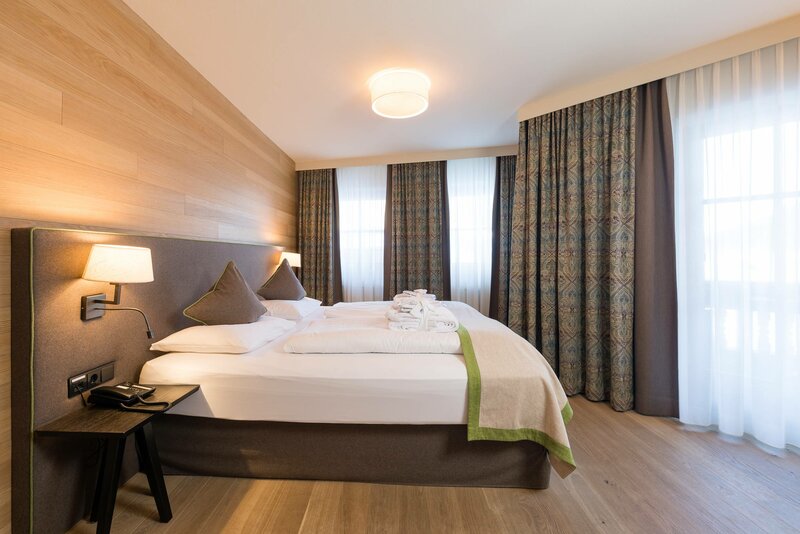 Der Schlafbereich mit einem großen Doppelbett und bodentiefen Fenstern in der Suite zum Wohlfühlen