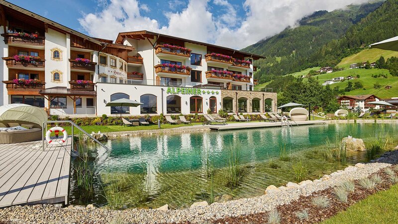 Der große Naturbadeteich und das Alpeiner Nature Resort mit der umliegenden Berglandschaft im Hintergrund