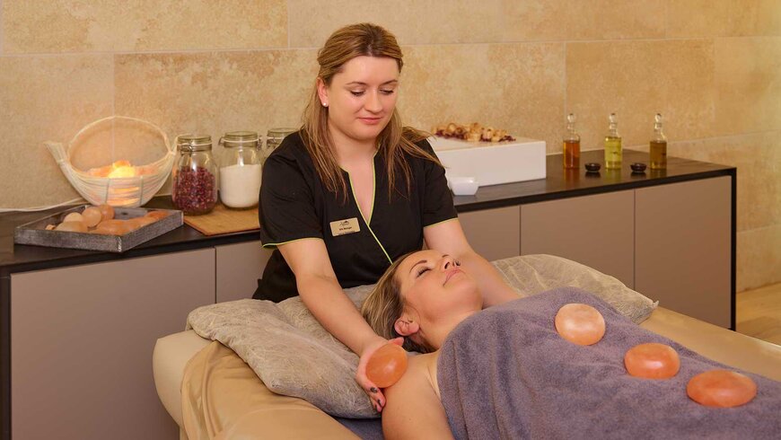 Frau genießt eine entspannende Massage mit heißen Steinen in einem Spa.