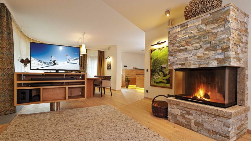 Einblick in den Wohnbereich mit großem Kamin und Flatscreen-TV einer Suite