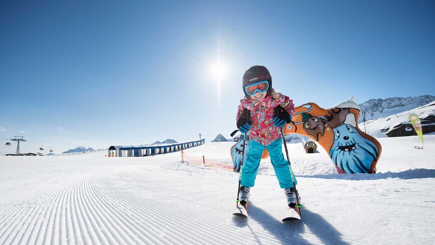 Ein Kind genießt das Skifahren auf einem sonnigen Gletscher in Tirol während des Sommerurlaubs mit der Familie.