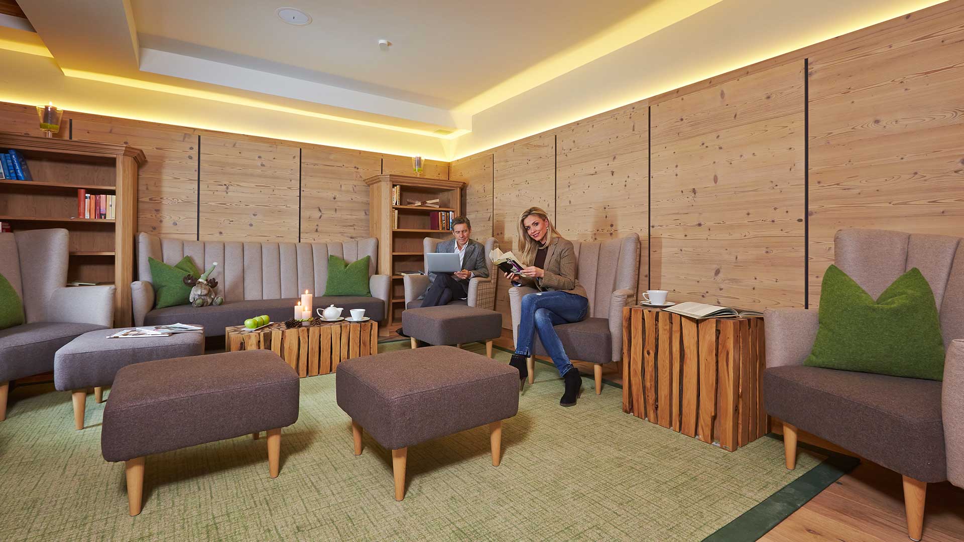 Ein gemütlicher Aufenthaltsraum des Nature Resorts in Tirol, in dem sich ein Mann und eine Frau entspannen und Bücher lesen.